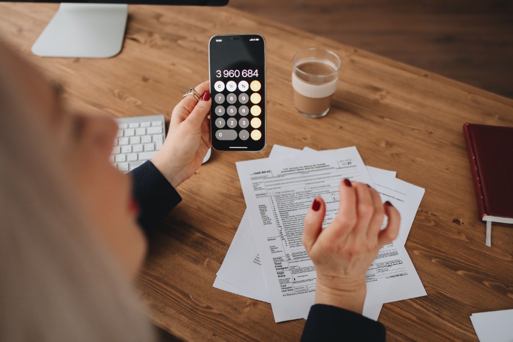 Owner adding up commissions on a phone calculator