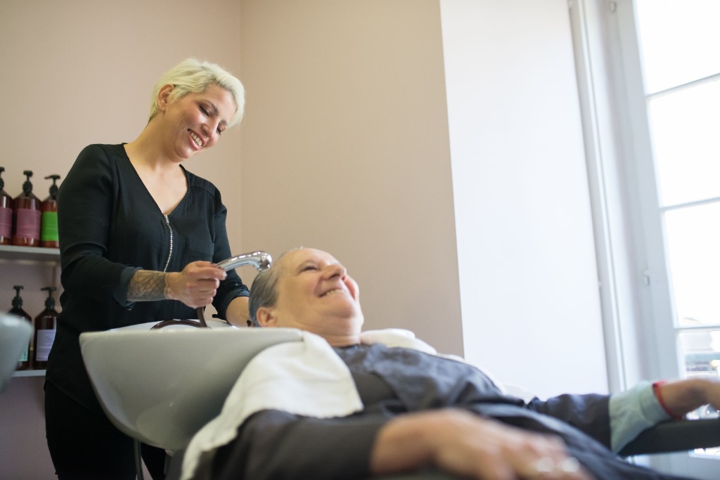 Stylist washing a client's hair at the basin